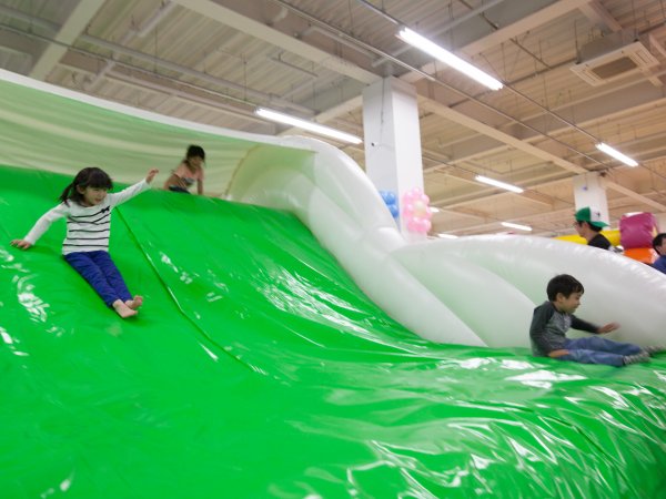 屋内の大きなふわふわ滑り台をすべる子どもたち