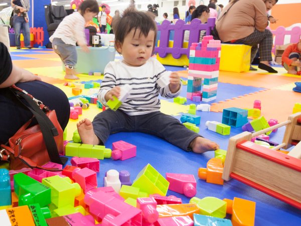 床に座って大型ブロックで遊ぶ赤ちゃん