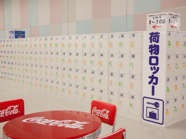 「荷物ロッカー」と書かれた案内板と、番号の付いた小型ロッカーの壁