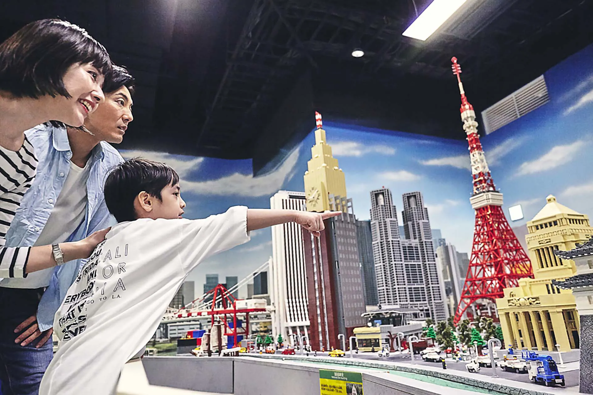 レゴで作られた東京タワーや高層ビルの街並みを見る家族