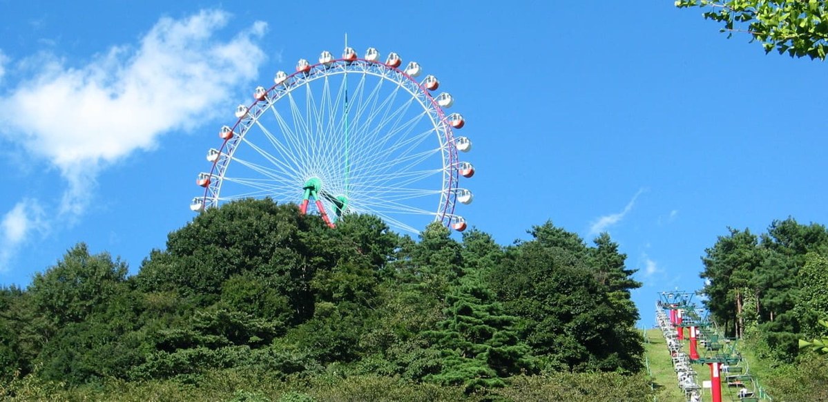 山の上に立つ観覧車と、まわりの緑