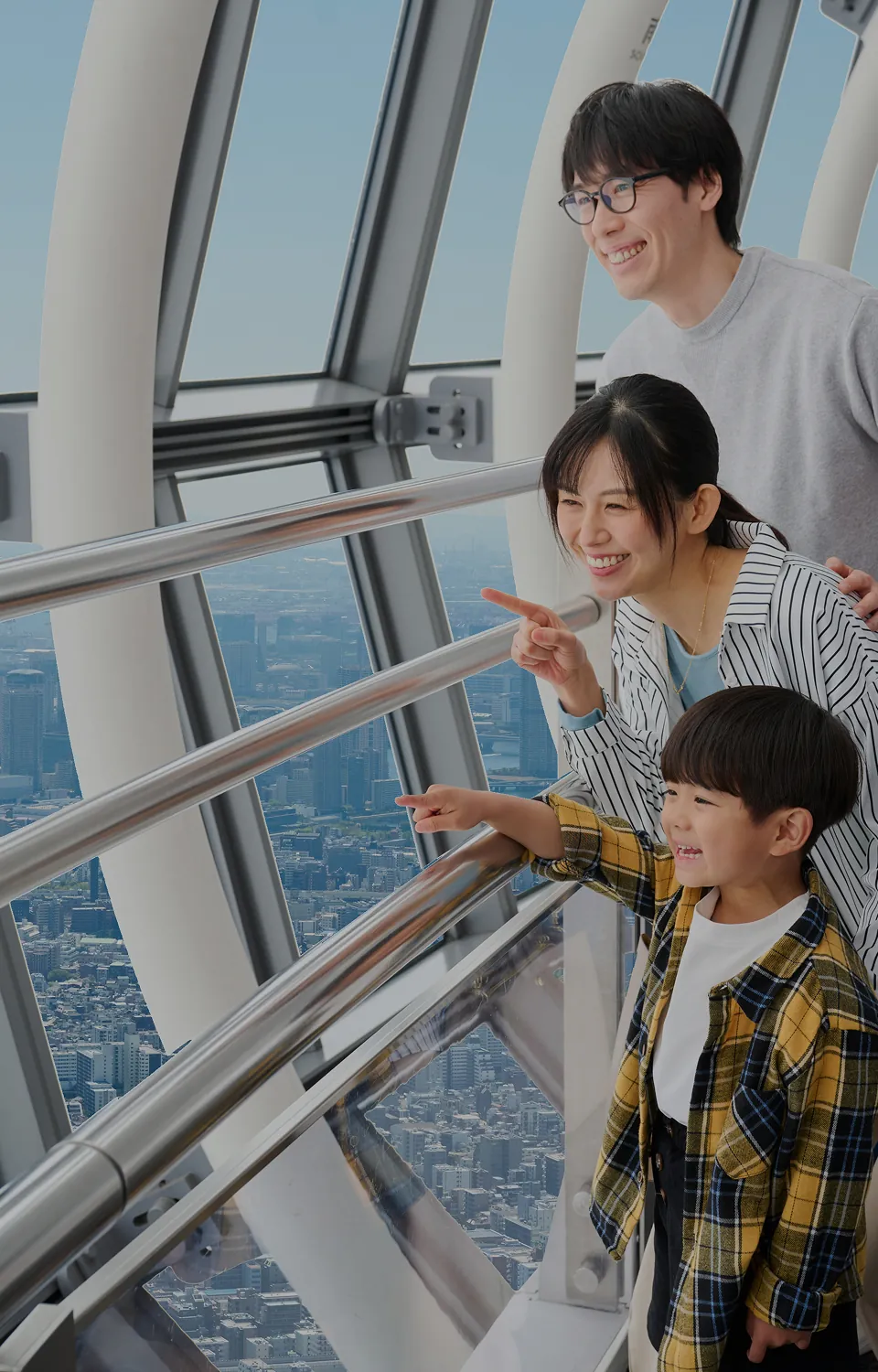 展望デッキの窓辺で外を指さす家族