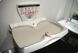 トイレの壁に、折りたたみ式のおむつ交換台が開いた状態で取り付けられている