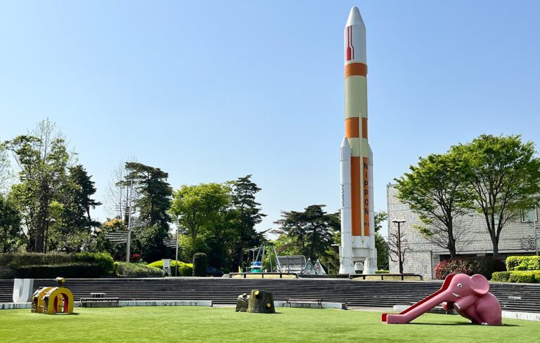 芝生の広場の奥に、白とオレンジの大きなロケットの模型が立っている