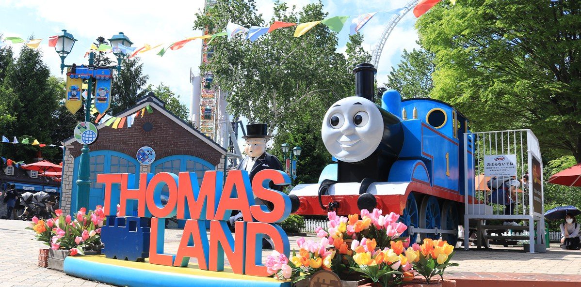 THOMAS LANDの立体文字の横に、実物大の青いトーマスの模型が置かれている。手前にチューリップの花壇