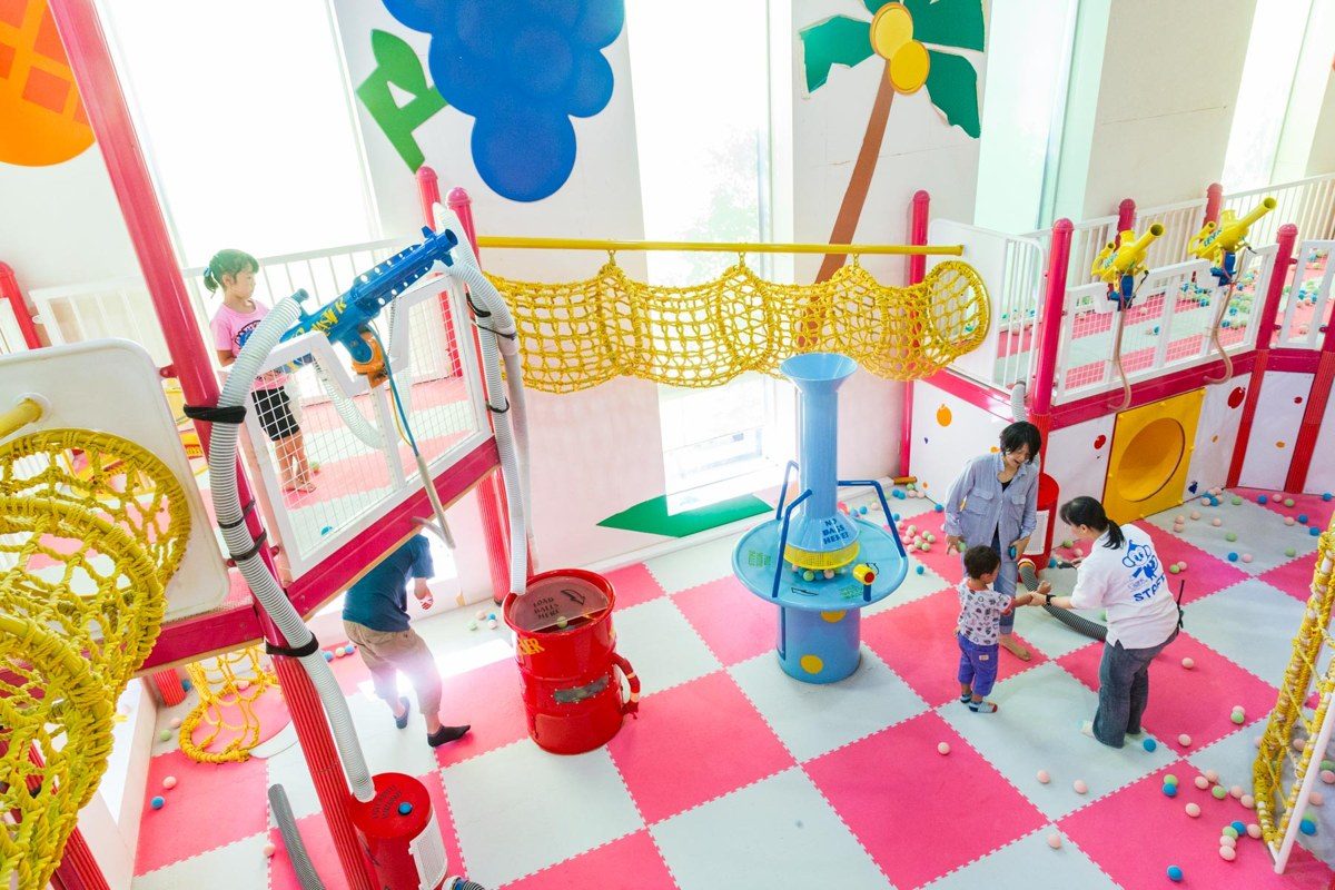 赤と白の床に遊具が並ぶ屋内のアスレチック