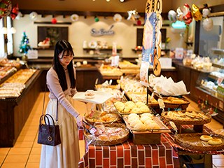 パン屋の店内。木の台の上に、焼きたてのパンがトレーごとずらりと並んでいる