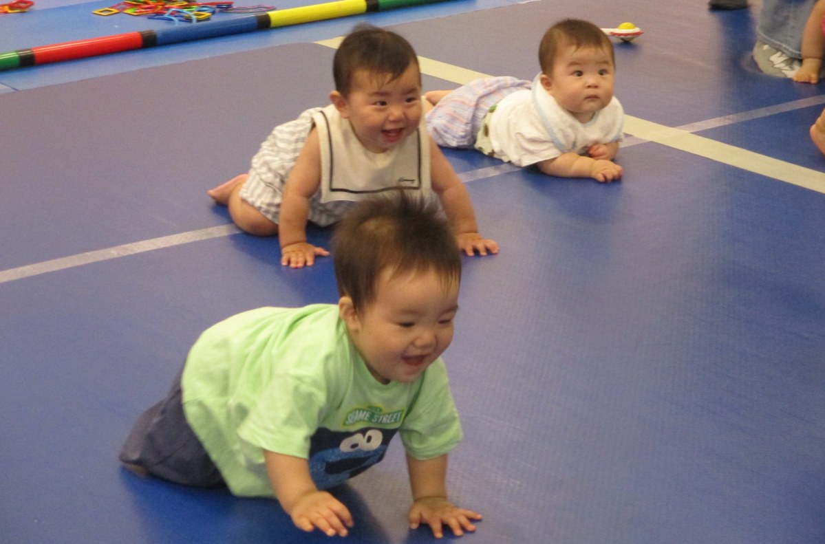 青いマットの上でハイハイする赤ちゃん3人