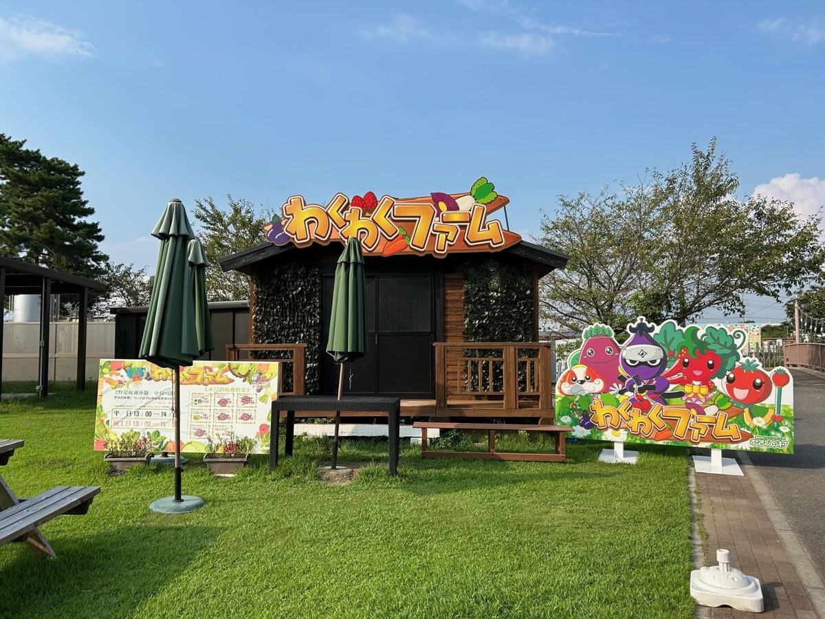 「わくわくファーム」の看板を掲げた芝生の上の木の小屋