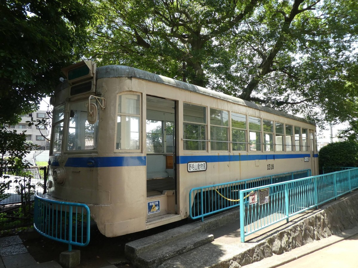 木立の下に置かれた白と青の路面電車の車両