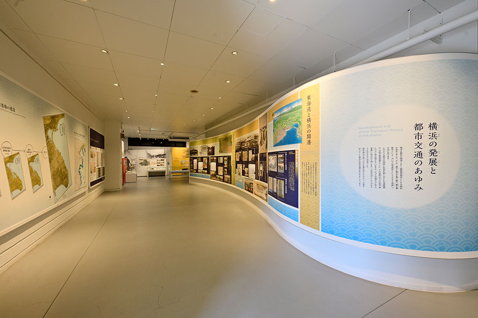 「横浜の発展と都市交通のあゆみ」と書かれた曲面の展示壁が続く、平らで広い通路
