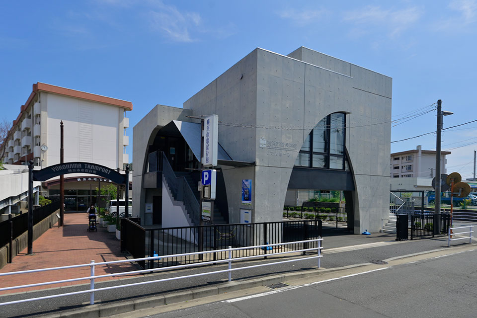 コンクリート打ちっぱなしのアーチのある建物と、その手前の「YOKOHAMA TRAMPORT」と書かれたアーチ