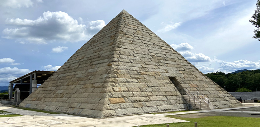 青空の下に建つ石積みのピラミッド