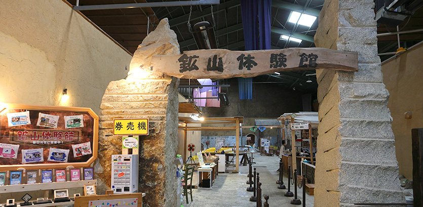 石の門に鉱山体験館の看板がかかる入口と館内