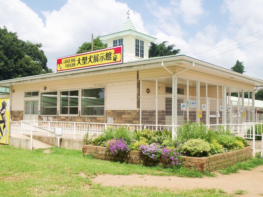 大型犬展示館と書かれた看板のある平屋の建物。手前に花壇がある