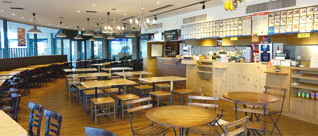 木のテーブルと椅子が並ぶレストランの店内