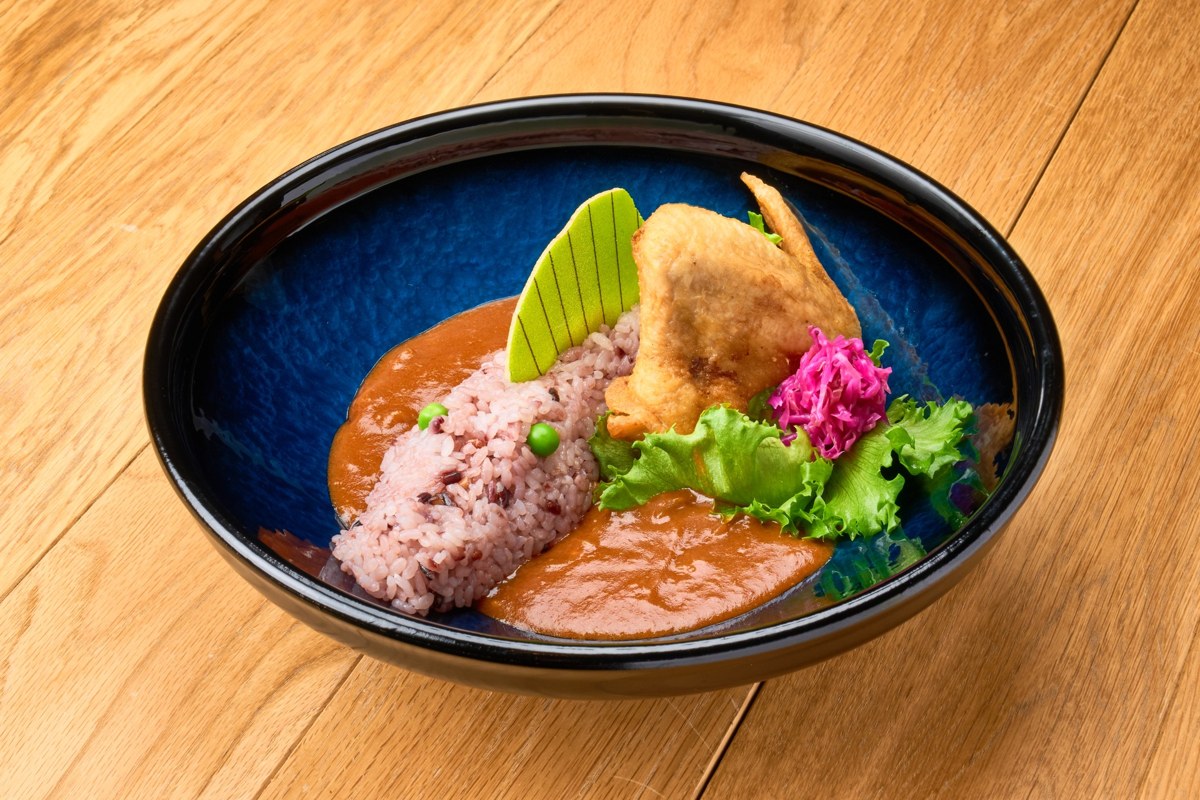 背びれの形のパイと手羽先のフライを添えたカレー