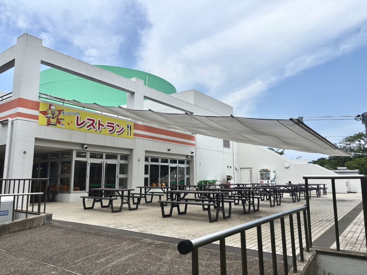 「レストラン」の看板と、日よけの下にテーブルが並ぶテラス席