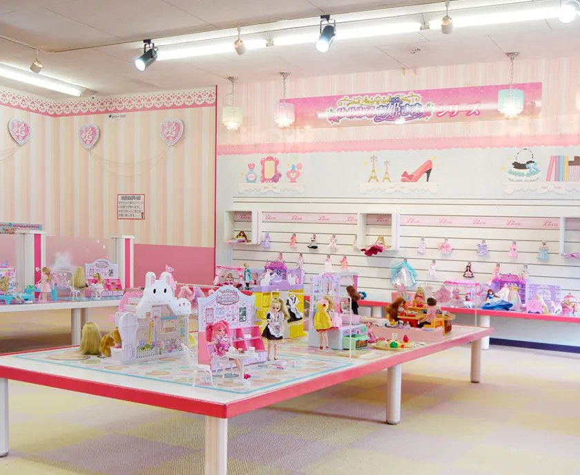 人形とドールハウスが大きなテーブルに並ぶピンクの部屋
